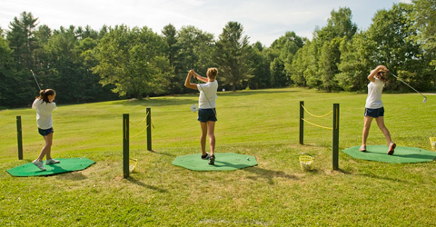 Three campers practicing their golf strokes.