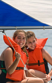 Two girls sail a boat on Tripp Lake.