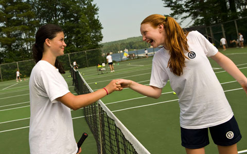 Two campers shake hands after a tennis match.