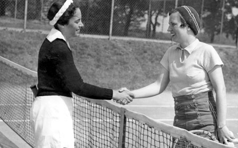 Two campers shake hands after a tennis match.