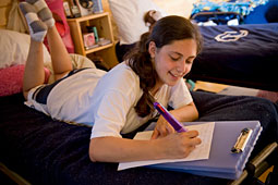 A young girl writing a letter home.